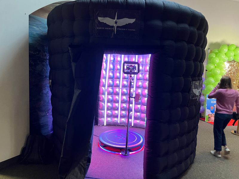 360 photo booth setup by White Heron Productions at an event in Minneapolis, featuring an inflatable enclosure and vibrant lighting.